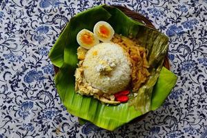 Nasi Liwet Solo or Sego Liwet Solo is a traditional food from Surakarta. made from savory rice, chayote and boiled egg, chicken, thick coconut milk served on a banana leaf photo