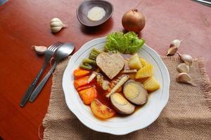 selat solo is traditional salad food from indonesia. made from hard-boiled eggs, boiled chickpeas, boiled carrots, hash browns and lettuce, steak or bistik. served on wood table photo