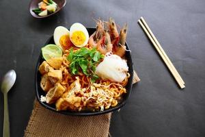 laksa, laksa curry made from vermicelli, noodles, bean sprouts, egg, tofu lime, and shrimp with a spicy soup sauce that is rich in spices. laksa served on bowl, isolated on white background. photo