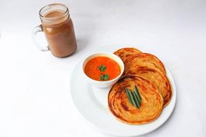 roti canai y teh tarik. pan paratha o pan canai o roti maryam, plato de desayuno favorito. servido en plato foto