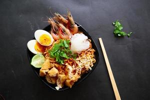 laksa, laksa curry made from vermicelli, noodles, bean sprouts, egg, tofu lime, and shrimp with a spicy soup sauce that is rich in spices. laksa served on bowl, isolated on white background. photo