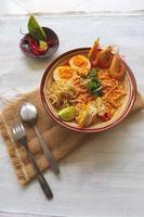 laksa, laksa curry made from vermicelli, noodles, bean sprouts, egg, tofu lime, and shrimp with a spicy soup sauce that is rich in spices. laksa served on bowl, isolated on white background. photo