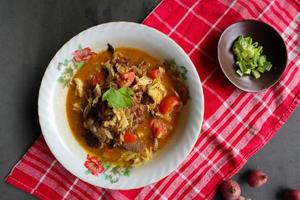 Goat Curry or gulai kambing, food from asia. Delicious goat meat curry served in a bowl.served with tomato, seasoning, celery and cabbage photo