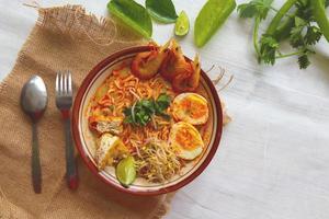 laksa, laksa curry made from vermicelli, noodles, bean sprouts, egg, tofu lime, and shrimp with a spicy soup sauce that is rich in spices. laksa served on bowl, isolated on white background. photo