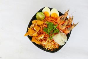 laksa, laksa curry made from vermicelli, noodles, bean sprouts, egg, tofu lime, and shrimp with a spicy soup sauce that is rich in spices. laksa served on bowl, isolated on white background. photo