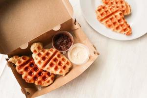 Croissant Waffle or Croffle with chocolate sauce served in box and white background photo