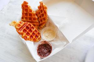 gofre croissant o croffle con salsa de chocolate servido en caja y fondo blanco foto