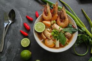 Tom yam soup originating from Thailand. Tom yum is made with shrimp, chili, lime, chicken, fish, or seafood and mushrooms. photo