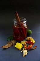 wedang uwuh is traditional herbal drink from indonesia. made from cinnamon, nutmeg and cloves leaves. Another ingredient is wood from the secang tree, ginger and lump sugar on black background photo