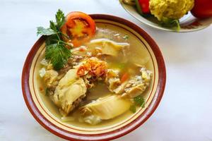 Chicken soup served with vegetables, tomatoes, celery in a bowl, spoon and fork. with black background photo