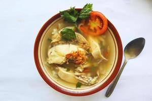 Chicken soup served with vegetables, tomatoes, celery in a bowl, spoon and fork. with black background photo