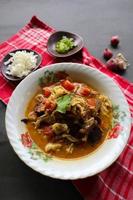 Goat Curry or gulai kambing, food from asia. Delicious goat meat curry served in a bowl.served with tomato, seasoning, celery and cabbage photo