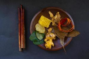 wedang uwuh is traditional herbal drink from indonesia. made from cinnamon, nutmeg and cloves leaves. Another ingredient is wood from the secang tree, ginger and lump sugar on black background photo