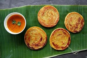 paratha bread or canai bread or roti maryam, favorite breakfast dish. served on banana leave photo