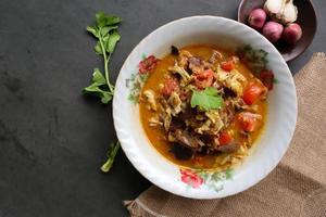 Goat Curry or gulai kambing, food from asia. Delicious goat meat curry served in a bowl.served with tomato, seasoning, celery and cabbage photo