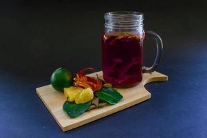 wedang uwuh es una bebida herbal tradicional de indonesia. hecho de hojas de canela, nuez moscada y clavo. otro ingrediente es la madera del árbol secang, el jengibre y el azúcar en trozos sobre fondo negro foto