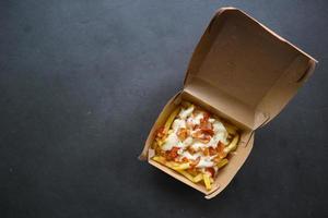 fried fries with with melted cheddar cheese or fried cheese with topping sausage slices on box photo