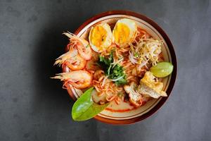 laksa, laksa curry made from vermicelli, noodles, bean sprouts, egg, tofu lime, and shrimp with a spicy soup sauce that is rich in spices. laksa served on bowl, isolated on white background. photo