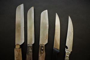 Many knifes lie on black background for cooking photo