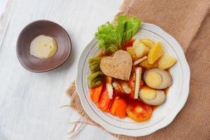 selat solo is traditional salad food from indonesia. made from hard-boiled eggs, boiled chickpeas, boiled carrots, hash browns and lettuce, steak or bistik. served on wood table photo