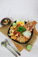 laksa, laksa curry made from vermicelli, noodles, bean sprouts, egg, tofu lime, and shrimp with a spicy soup sauce that is rich in spices. laksa served on bowl, isolated on white background. photo