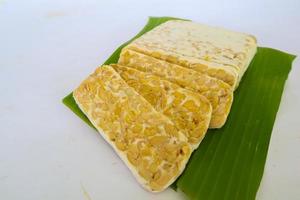 Raw tempeh or tempe. tempeh slices in white background. raw soybean seeds. Tempe is a traditional Indonesian food made from fermented soybeans. photo