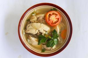 Chicken soup served with vegetables, tomatoes, celery in a bowl, spoon and fork. with black background photo