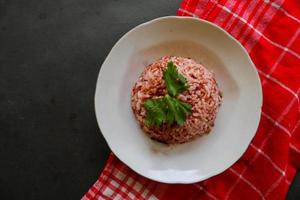 Red steamed rice or nasi merah served in plate isolated on black background photo