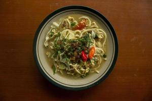 Mie godog Jawa or bakmi jawa or java noodle or Mie rebus or boiled noodles with spoon and fork. Indonesian traditional street food noodles from java, indonesia on white backgroud photo