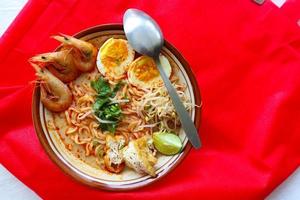 laksa, laksa curry made from vermicelli, noodles, bean sprouts, egg, tofu lime, and shrimp with a spicy soup sauce that is rich in spices. laksa served on bowl, isolated on white background. photo
