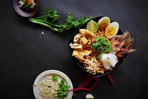 laksa, laksa curry made from vermicelli, noodles, bean sprouts, egg, tofu lime, and shrimp with a spicy soup sauce that is rich in spices. laksa served on bowl, isolated on white background. photo