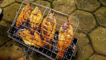 pescado a la parrilla, pescado a la parrilla tilapia del nilo a la parrilla sobre carbón caliente foto