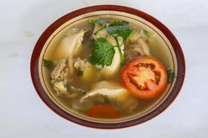 Chicken soup served with vegetables, tomatoes, celery in a bowl, spoon and fork. with black background photo