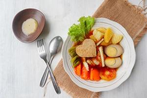 selat solo is traditional salad food from indonesia. made from hard-boiled eggs, boiled chickpeas, boiled carrots, hash browns and lettuce, steak or bistik. served on wood table photo