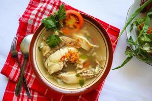 Chicken soup served with vegetables, tomatoes, celery in a bowl, spoon and fork. with black background photo