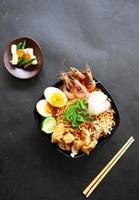 laksa, laksa curry made from vermicelli, noodles, bean sprouts, egg, tofu lime, and shrimp with a spicy soup sauce that is rich in spices. laksa served on bowl, isolated on white background. photo
