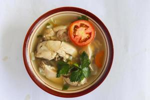 Chicken soup served with vegetables, tomatoes, celery in a bowl, spoon and fork. with black background photo