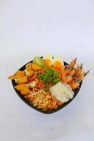 laksa, laksa curry made from vermicelli, noodles, bean sprouts, egg, tofu lime, and shrimp with a spicy soup sauce that is rich in spices. laksa served on bowl, isolated on white background. photo