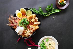laksa, laksa curry made from vermicelli, noodles, bean sprouts, egg, tofu lime, and shrimp with a spicy soup sauce that is rich in spices. laksa served on bowl, isolated on white background. photo