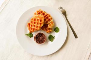 gofre croissant o croffle con salsa de chocolate servido en caja y fondo blanco foto