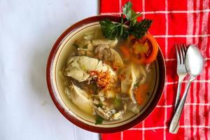 Chicken soup served with vegetables, tomatoes, celery in a bowl, spoon and fork. with black background photo