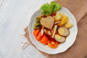 selat solo is traditional salad food from indonesia. made from hard-boiled eggs, boiled chickpeas, boiled carrots, hash browns and lettuce, steak or bistik. served on wood table photo