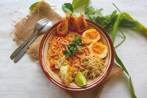 laksa, laksa curry made from vermicelli, noodles, bean sprouts, egg, tofu lime, and shrimp with a spicy soup sauce that is rich in spices. laksa served on bowl, isolated on white background. photo