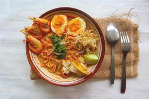 laksa, laksa curry made from vermicelli, noodles, bean sprouts, egg, tofu lime, and shrimp with a spicy soup sauce that is rich in spices. laksa served on bowl, isolated on white background. photo