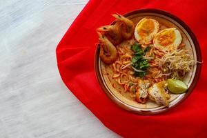 laksa, laksa curry made from vermicelli, noodles, bean sprouts, egg, tofu lime, and shrimp with a spicy soup sauce that is rich in spices. laksa served on bowl, isolated on white background. photo