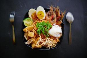 laksa, laksa curry made from vermicelli, noodles, bean sprouts, egg, tofu lime, and shrimp with a spicy soup sauce that is rich in spices. laksa served on bowl, isolated on white background. photo
