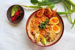 laksa, laksa curry made from vermicelli, noodles, bean sprouts, egg, tofu lime, and shrimp with a spicy soup sauce that is rich in spices. laksa served on bowl, isolated on white background. photo