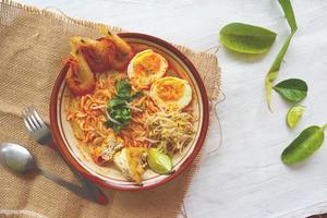 laksa, laksa curry made from vermicelli, noodles, bean sprouts, egg, tofu lime, and shrimp with a spicy soup sauce that is rich in spices. laksa served on bowl, isolated on white background. photo