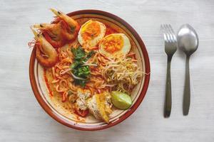 laksa, laksa curry made from vermicelli, noodles, bean sprouts, egg, tofu lime, and shrimp with a spicy soup sauce that is rich in spices. laksa served on bowl, isolated on white background. photo
