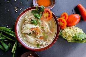 Chicken soup served with vegetables, tomatoes, celery in a bowl, spoon and fork. with black background photo
